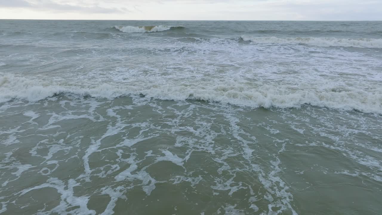 하얀 모래 해변, 흐린 날, 파도에 의해 손상된 해안 모래 언덕, 해안 침식, 기후 변화, 앞으로 나아가는 넓고 낮은 드론 샷