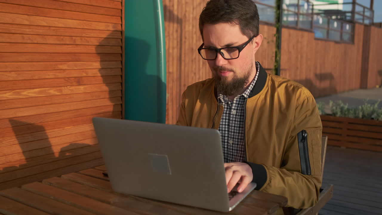 hombre trabajando en una computadora portátil en un café al aire libre
