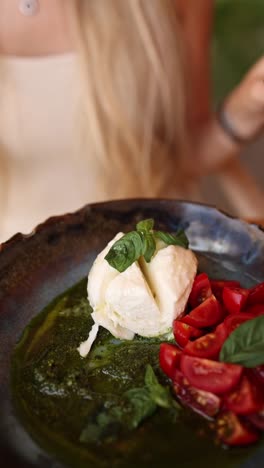 mujer comiendo ensalada de mozzarella con pesto