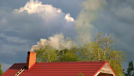 still landscape view of smoke coming from brick chimney from residential housing home property tiled rooftop with clouds in sky on countryside rural suburbs village town