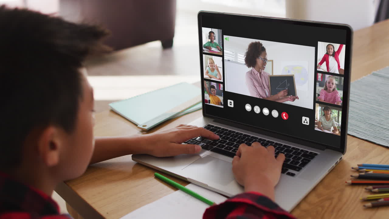 niño asiático teniendo una videoconferencia con el maestro y sus compañeros de clase en la computadora portátil en casa