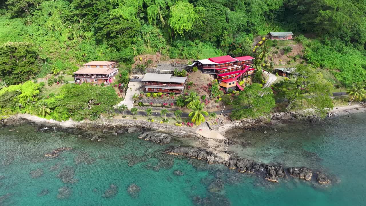 Small hotels, accomodation on the tropical shoreline Vanua Levu Island, Fiji, drone pull back.