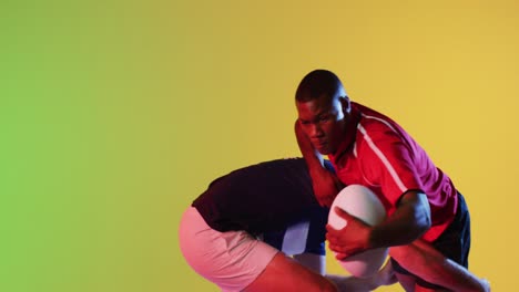 Diverse-male-rugby-players-with-rugby-ball-playing-over-yellow-lighting