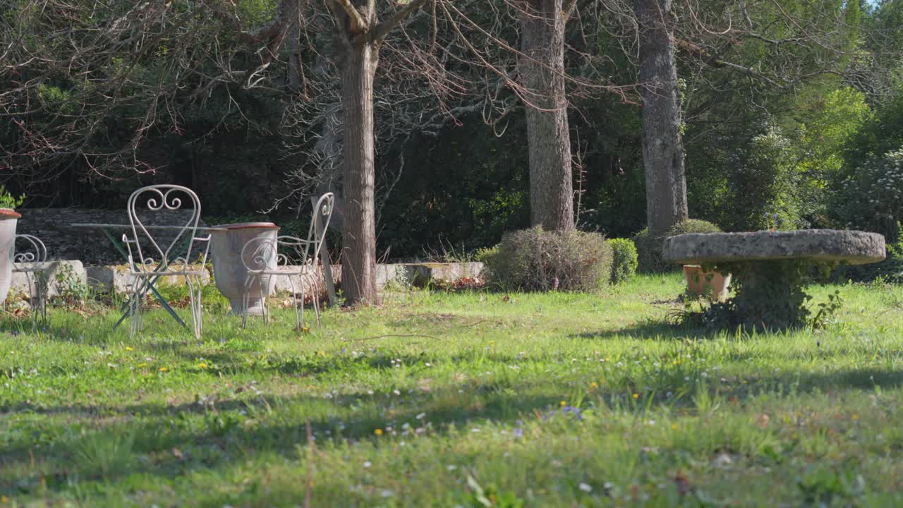 태양 아래에 앉아있는 테이블과 의자와 함께 정원의 낮은 드러내는  ⁇