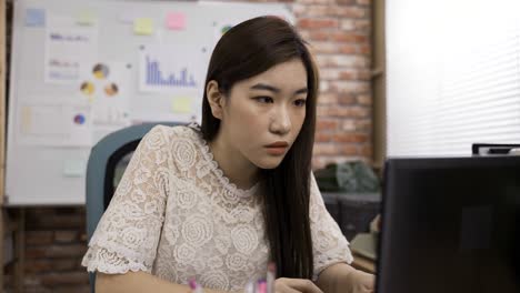 korean female creative worker is nodding head realizing the meaning of massage while propping face and looking at laptop screen in contemplation at office desk.