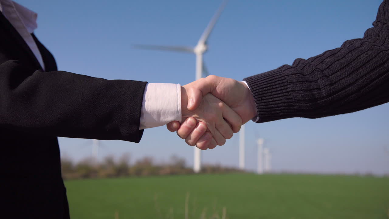 Handshake in front of wind turbines