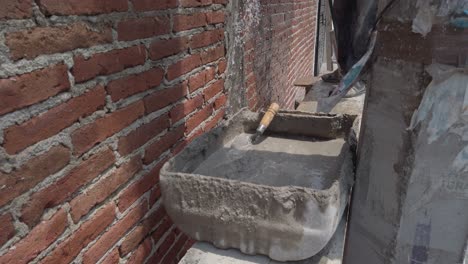 fresh cement mix in a tray with a trowel on a brick wall construction site