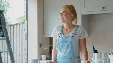 Retrato-De-Una-Mujer-Sonriente-Vistiendo-Petos-Renovando-La-Cocina-En-Casa