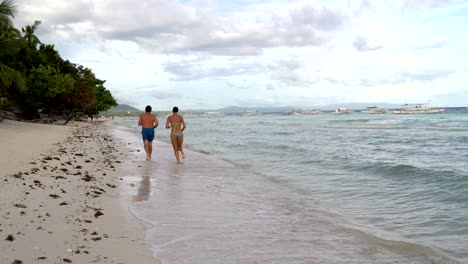 un hombre con una mujer corriendo por la playa