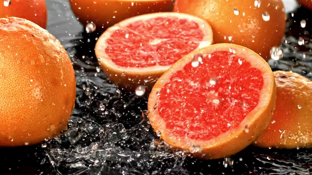 Pompelmi rinfrescanti con schizzi d'acqua su una superficie scura