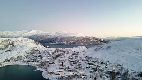 aerial establishing shot of ersfjordvegen surrounded by snowy mountains