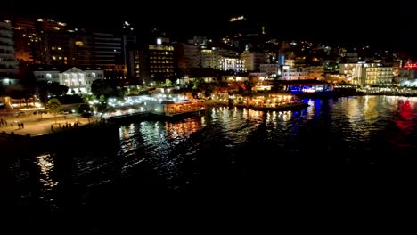 Noche-Espléndida-En-Saranda:-El-Paseo-Iluminado-Brilla-Sobre-Las-Tranquilas-Aguas-Del-Mar,-Mostrando-La-Belleza-Nocturna-De-La-Ciudad-Costera