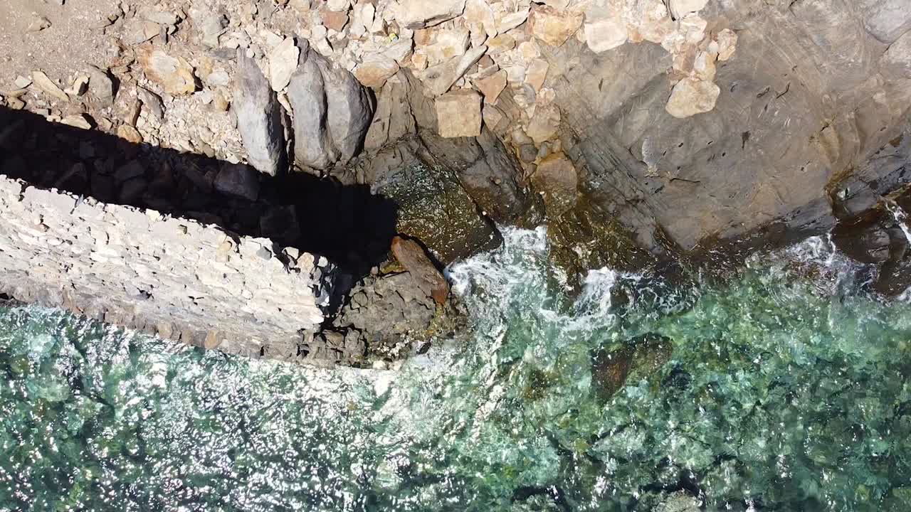 Aerial drone birds eye view of damaged sea wall erosion on coastline collapsed into the sea, ocean waves crashing onto shore at high tide on a remote tropical island in South East Asia
