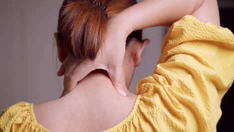 an asian woman massages the back of her neck to reduce high blood pressure