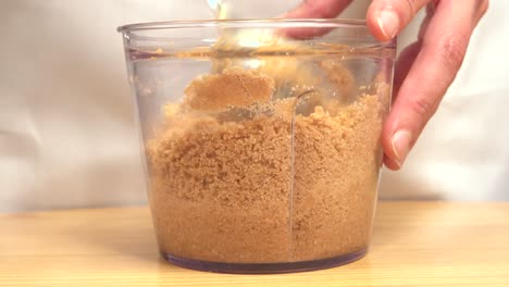 stirring crushed biscuits to prepare cake base in bowl with metal spoon