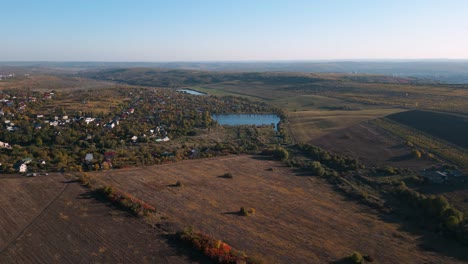 Vuelo-Aéreo-De-Drones-En-Otoño-De-Codru,-Chisinau,-Moldavia-En-2022---Campos-Coloridos-Y-árboles-Con-Un-Lago-De-Pesca-En-El-Centro---Lugares-Románticos-Para-Viajar-En-Las-Regiones-Vinícolas-De-Moldavia