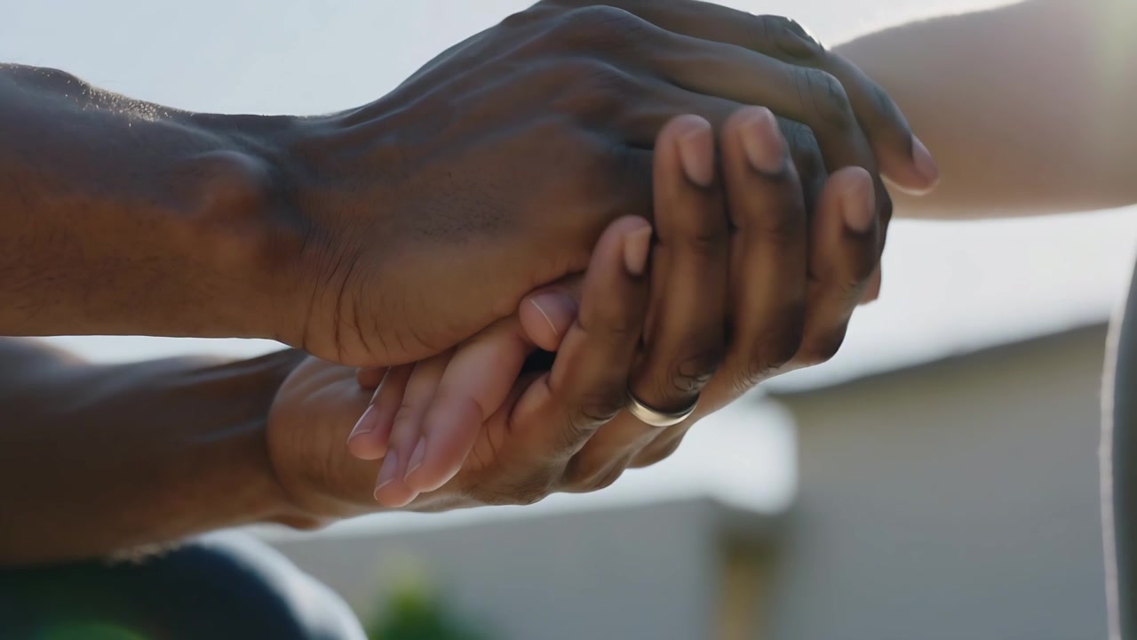 Reaching darker hand layering another, adults holding hands near home, ring on hand comforting