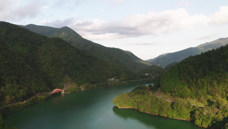 aguas tranquilas del lago okutama con puente mugiyama y montañas verdes en un día soleado en okutama, japón