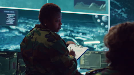 female brigadier general gather intelligence reports on a big screen