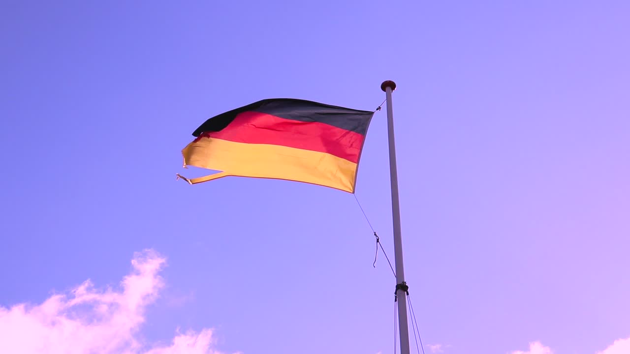Vind blæser det tyske flag med bevægende skyer og blå himmel i baggrunden