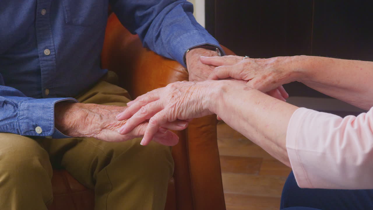 una pareja de ancianos amorosos disfrutando de la jubilación sentados en el sofá en casa tomados de la mano