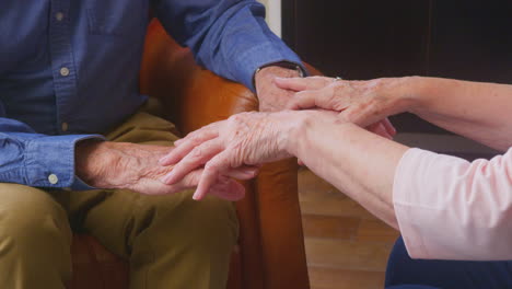 loving senior couple enjoying retirement sitting on sofa at home holding hands together