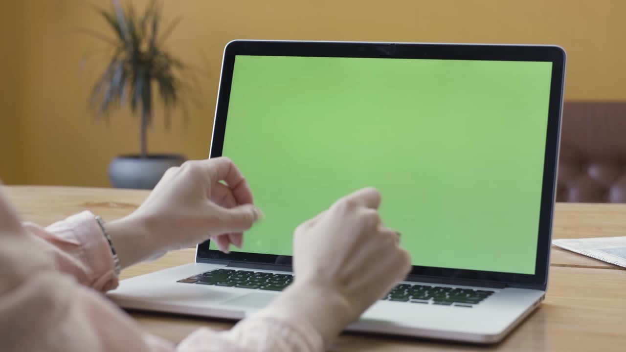 mujer escribiendo en una computadora portátil con pantalla verde
