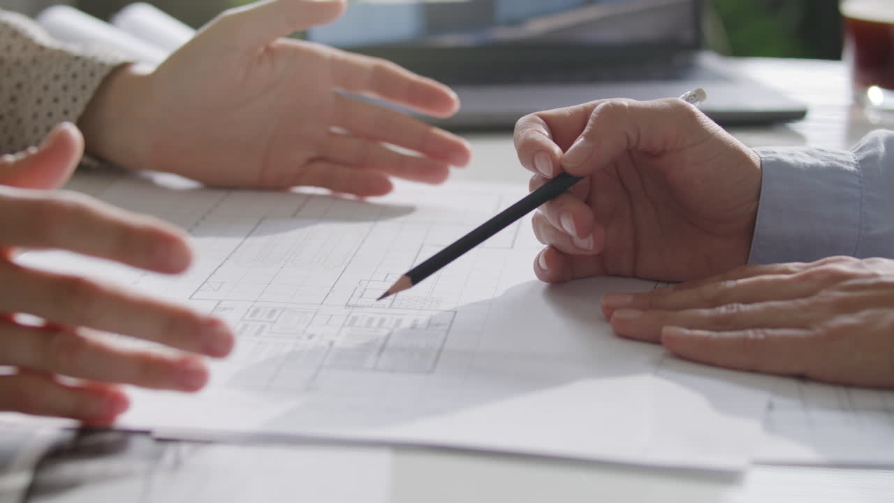 Hands of Two Female Colleagues Discussing Architectural Plan Details