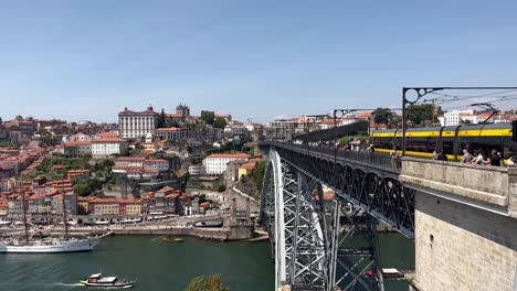 Panoramic-shot-of-Porto-City-with-train-crossing-Douro-River-on-Bridge-during-sunny-day---Beautiful-old-buildings-in-old-town-with-blue-sky---establishing-shot