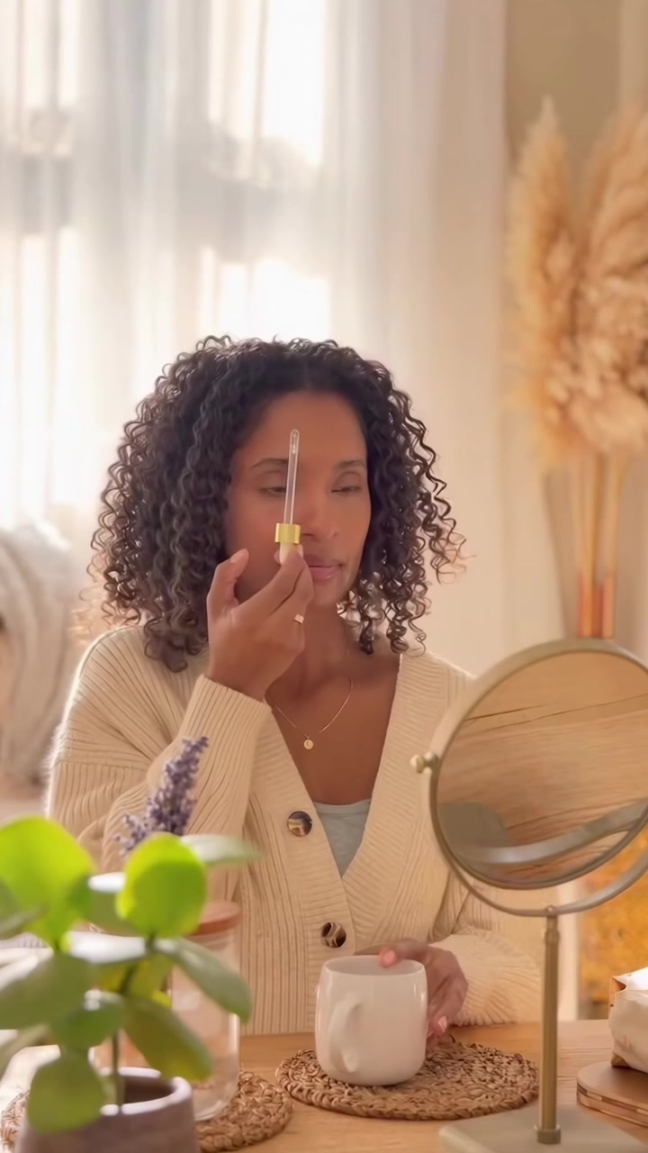 Woman Massaging Face with Skincare Serum in Bright Room