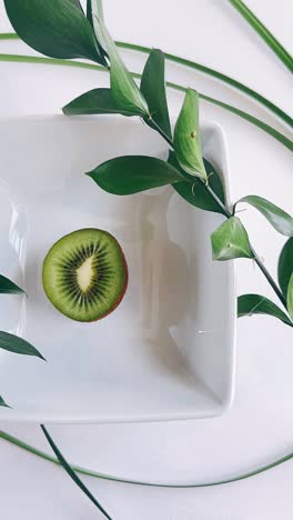 una rebanada de kiwi en un plato blanco con vegetación
