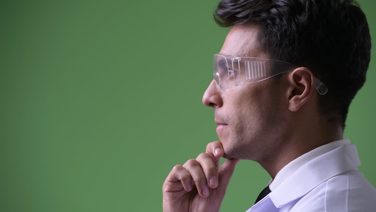 Giovane e affascinante medico ispanico su sfondo verde.