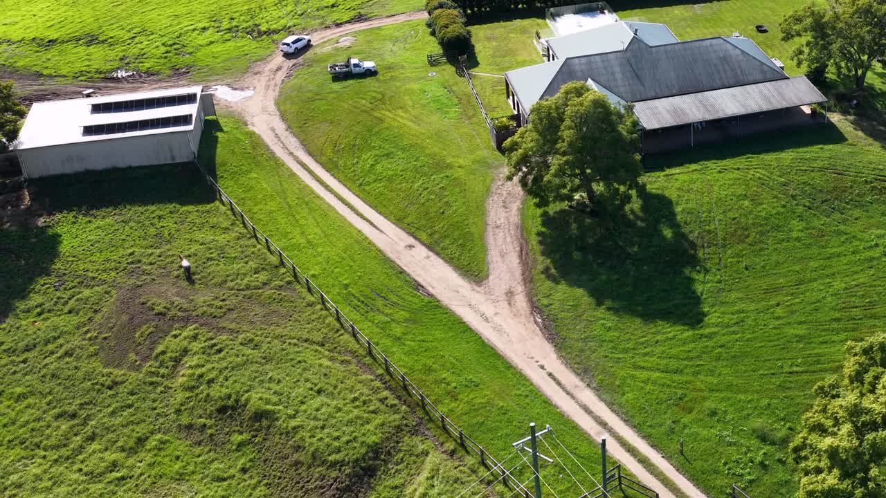 Aerial footage captures a rural property with buildings, greenery, and pathways in Uki, NSW, under bright daylight