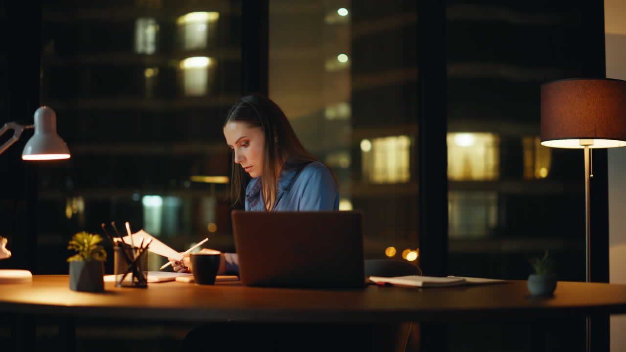 Overtime employee working online project writing notes in notebook. Serious lady