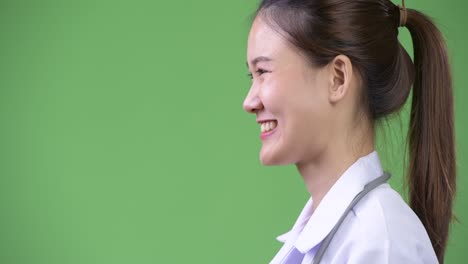profile view of young happy beautiful asian woman doctor smiling