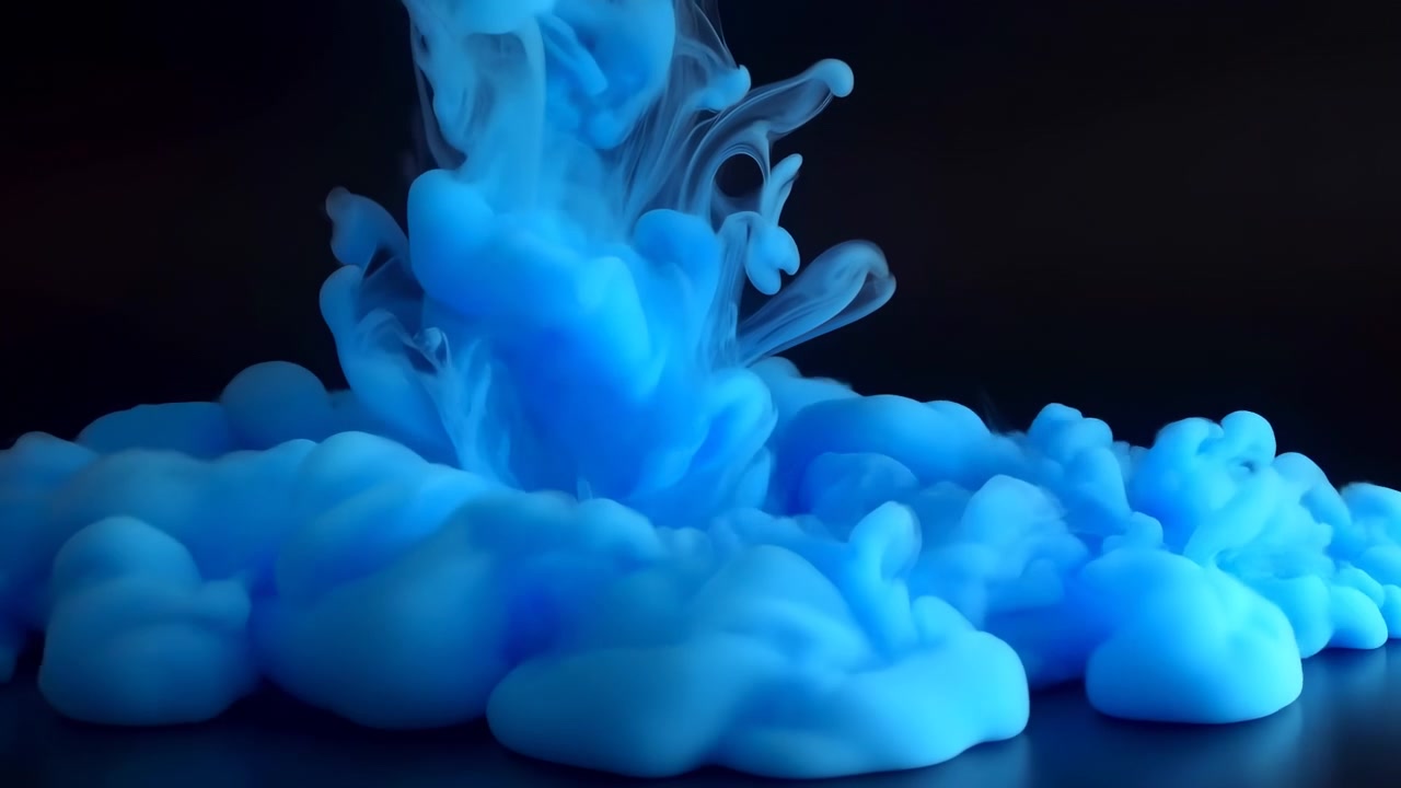 Liquido blu vivido si disperde in una scena scura mentre morbide forme ondeggianti si espandono verso l'esterno, mentre sottili volute arricciate si alzano e si attorcigliano sopra dense nuvole arrotondate vicino alla base.