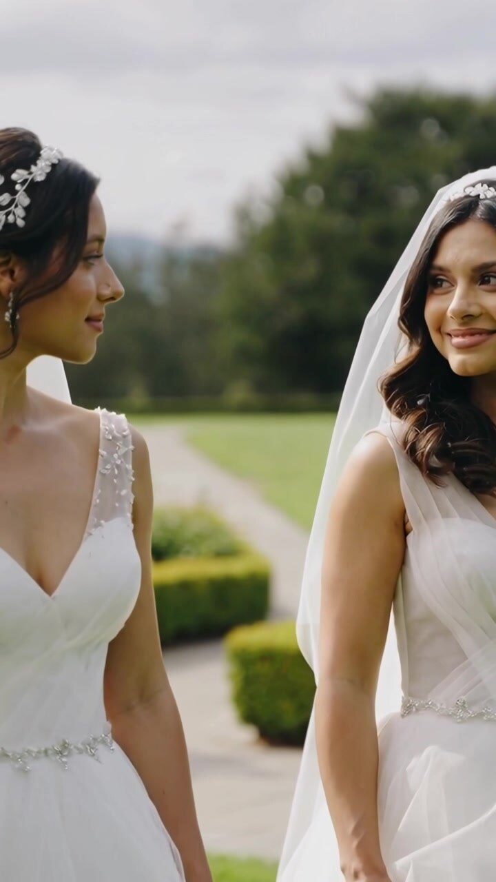Vertical video: Camera panning revealing two brides smiling in garden for vows with veils and gowns