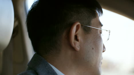 Close-Up-View-Of-Face-Of-Concentrated-Middle-Aged-Man-In-Glasses-Driving-Car-On-City-Road-In-The-Morning