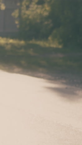 running boy with black schoolbag jumps up on grey asphalt road and throws copybooks after exam slow motion backside view