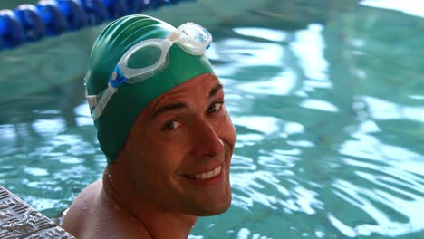 fit swimmer smiling up at camera in the swimming pool