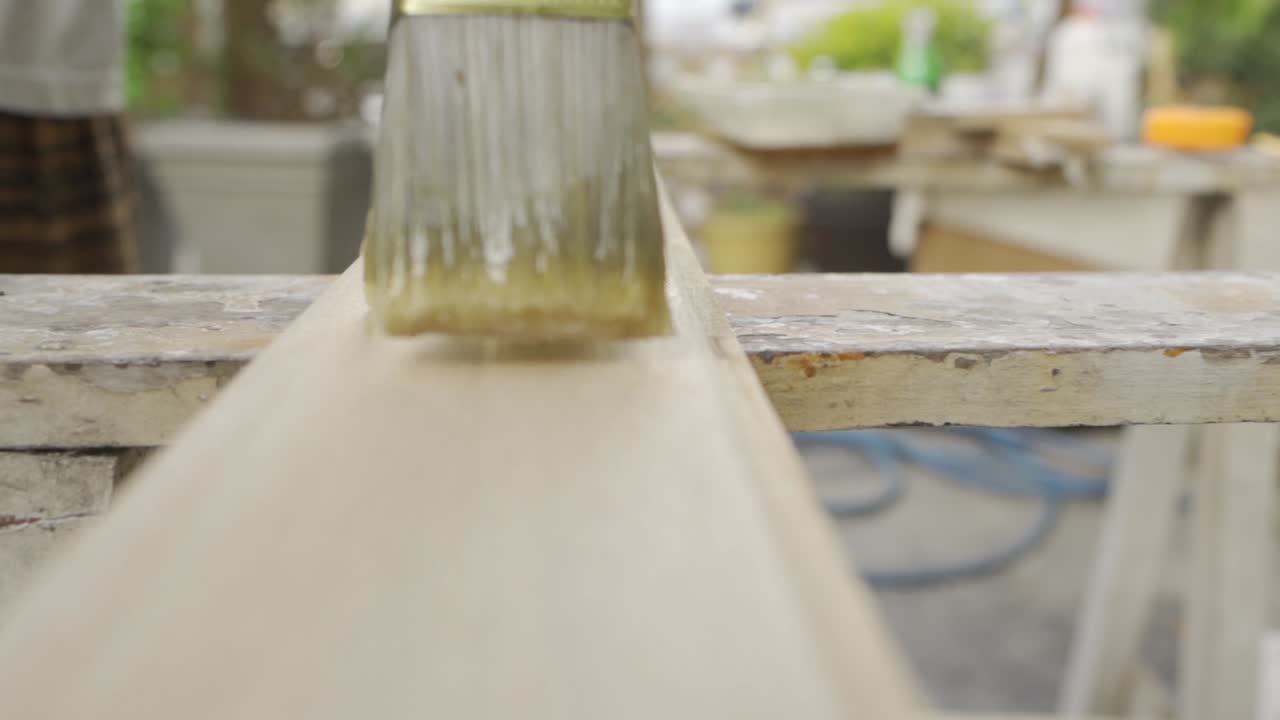 페인트 브러시로 나무 판자를 니스 칠하기