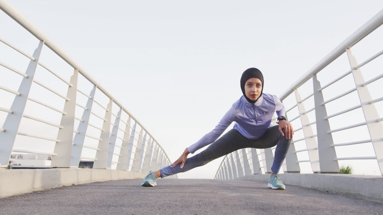 Woman wearing hijab stretching outside