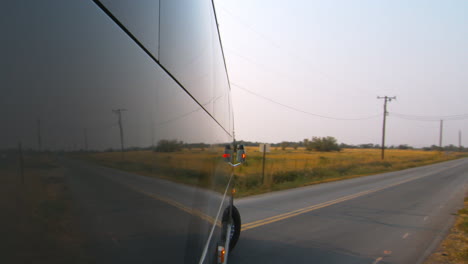 Side-view-of-a-public-bus,-shuttle,-or-school-bus-driving-and-the-road-reflection-on-it