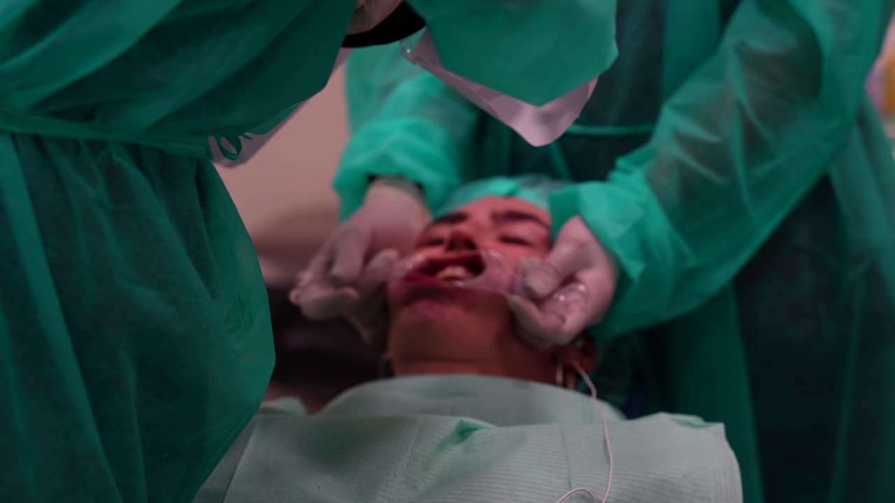 Rack focus shot of dentist photographing patient's mouth while assistant uses cheek retractor