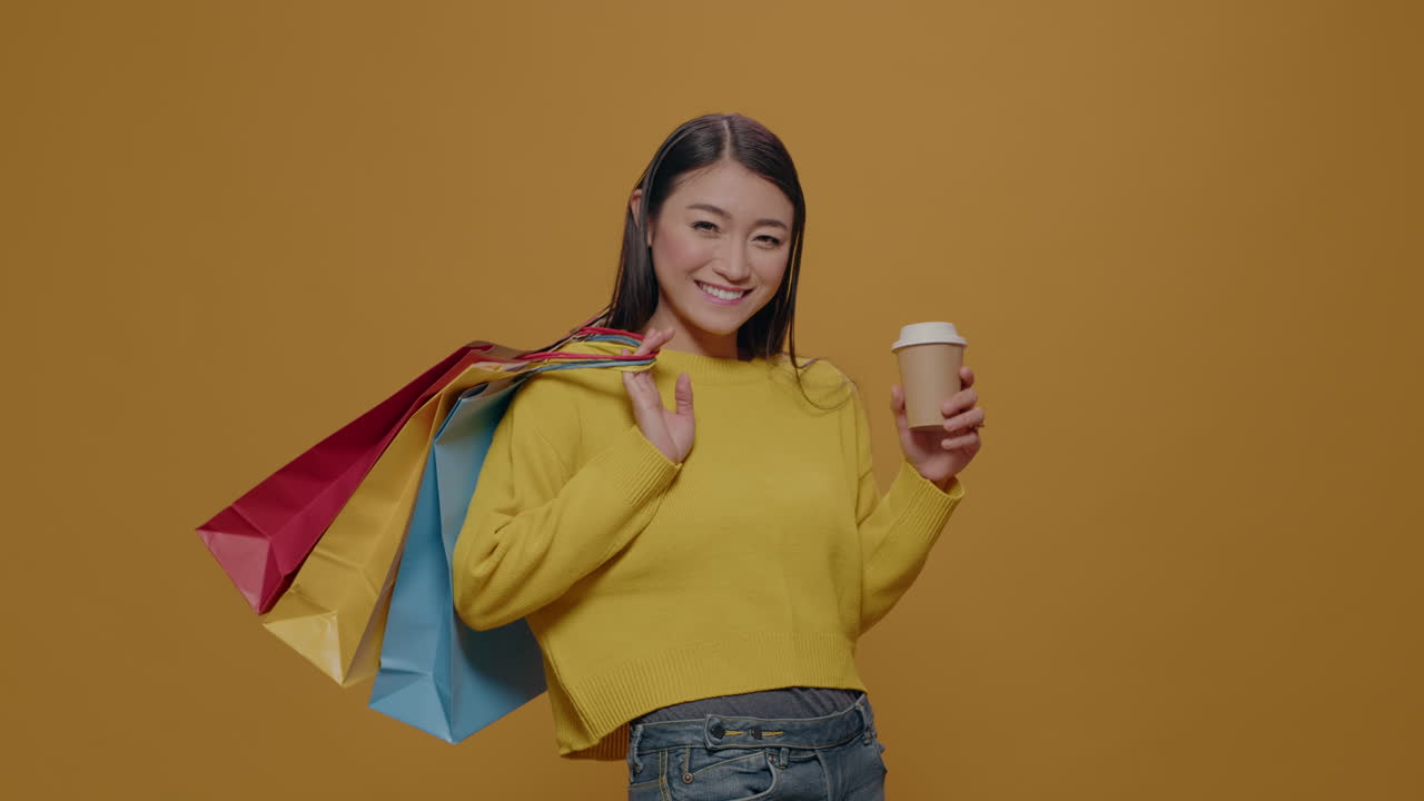 Positive adult posing with shopping bags and cup of coffee