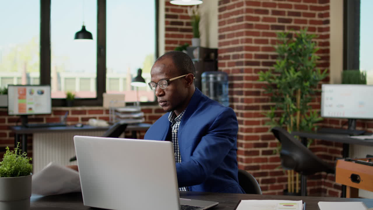 Company employee analyzing project information on papers and laptop