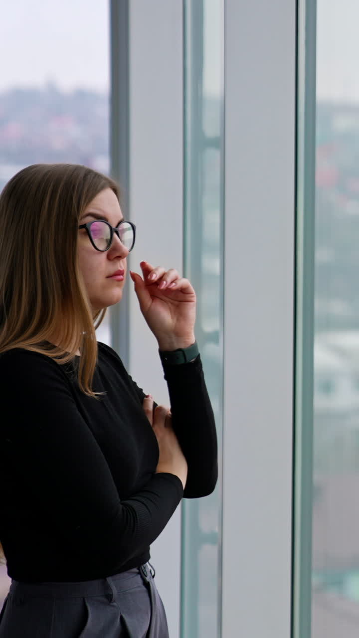 woman in eyeglasses while standing by the window Vertical video
