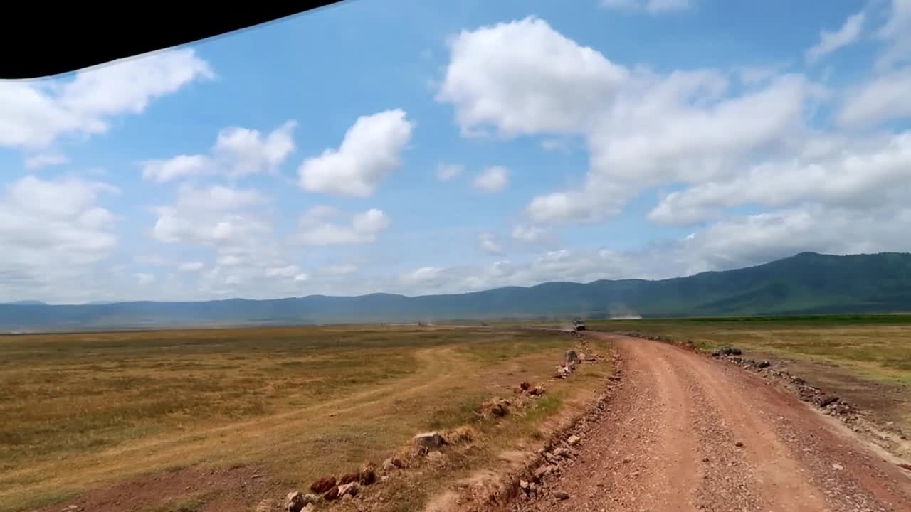 amplia vista del cráter ngorongoro desde un camión 4x4 mientras conduce por una carretera llena de baches