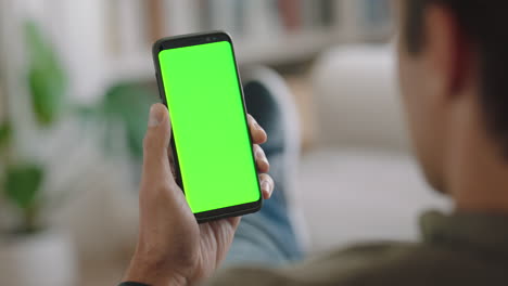 young-man-using-smartphone-watching-green-screen-enjoying-entertainment-on-mobile-phone-chroma-key-display-vertical-orientation-4k-footage