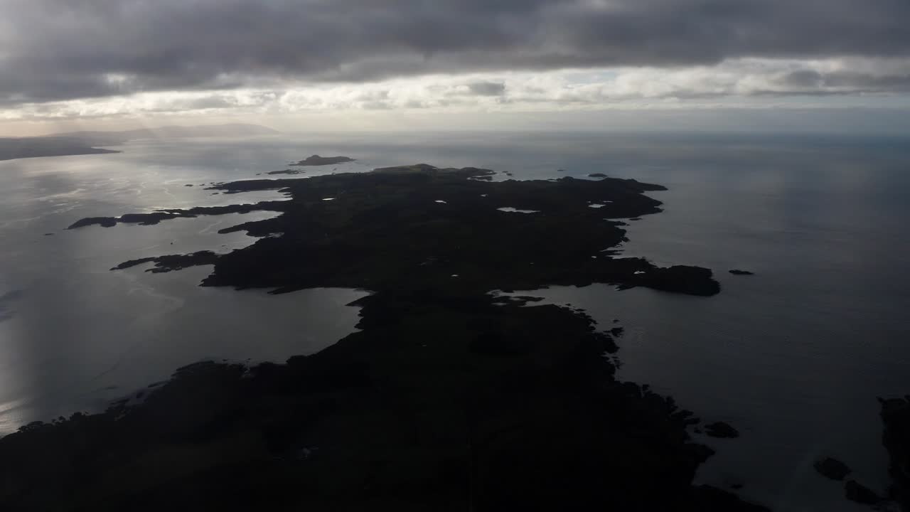 AERIAL - Epic silhouette of the Isle of Gigha at sunrise, Kintyre, Scotland, rising